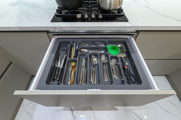 Open drawer with cutlery at modern white woden kitchen in classic style