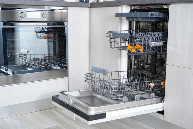 Photo open empty automatic dishwasher in the kitchen