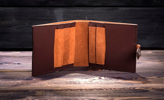 Open empty leather wallet on rustic wood background