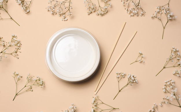 Open empty noodle bowl with and pair of wooden sticks on beige background top view