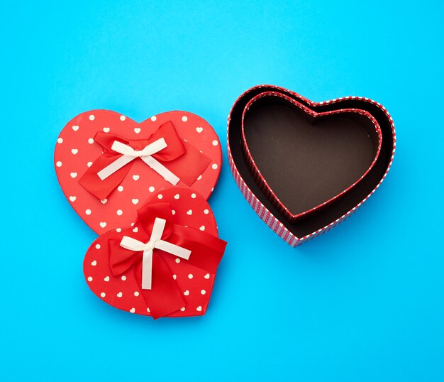 Open empty red cardboard box in the form of a heart on a light blue background