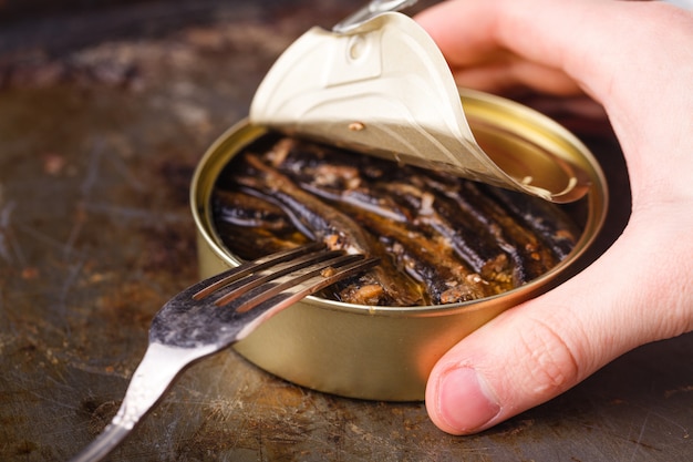 Open fish can and fork on table