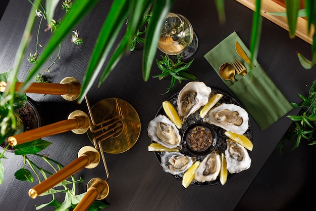 Open fresh oysters on a metal plate in ice on a concrete background