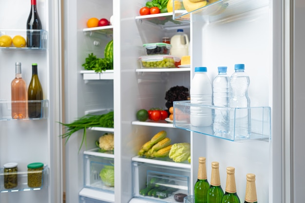 open fridge full of fresh fruits, vegetables and drinks