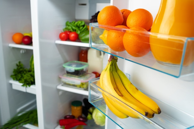Open fridge full of fresh fruits, vegetables and drinks