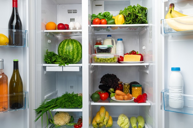 Open fridge full of fruits, vegetables and drinks