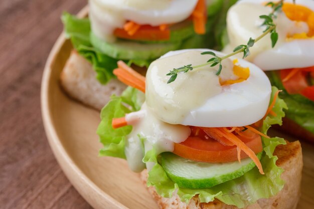 Open geconfronteerd sandwich met toast en groente en gekookt eitje met saladedressing.