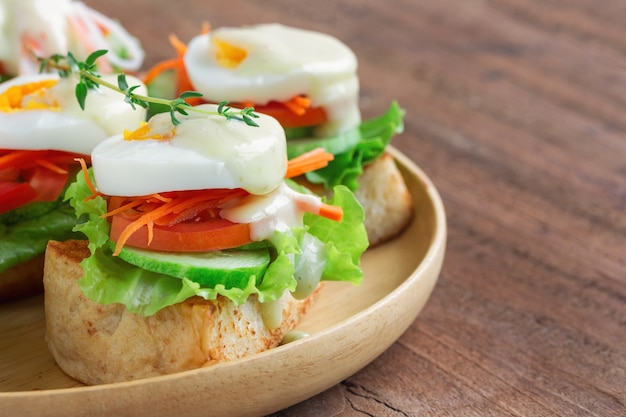 Open geconfronteerd sandwich met toast en groente en gekookt eitje met saladedressing.