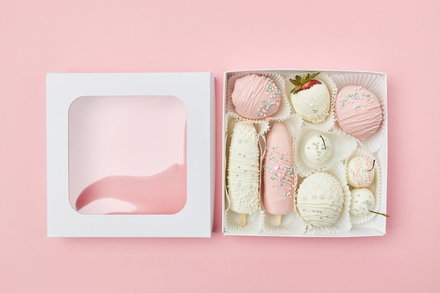 Open gift box with fruits covered in white and pink chocolate 