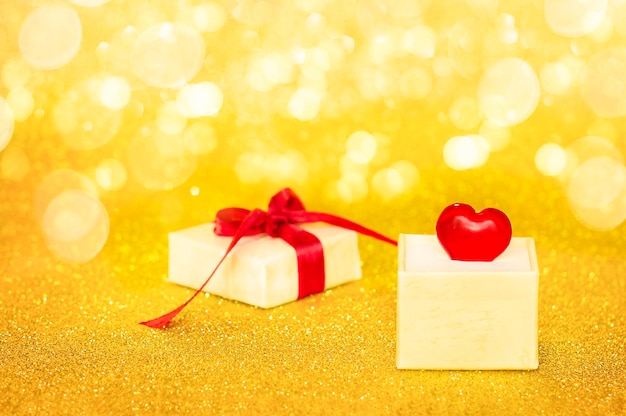 an open gift box with a heart lies on a golden background with bokeh