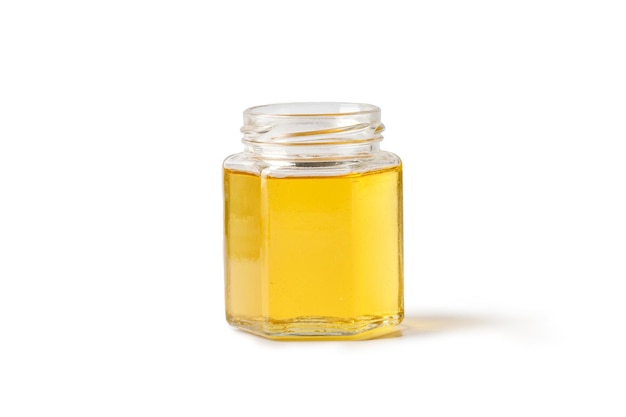 Open glass jar of honey isolated on a white background