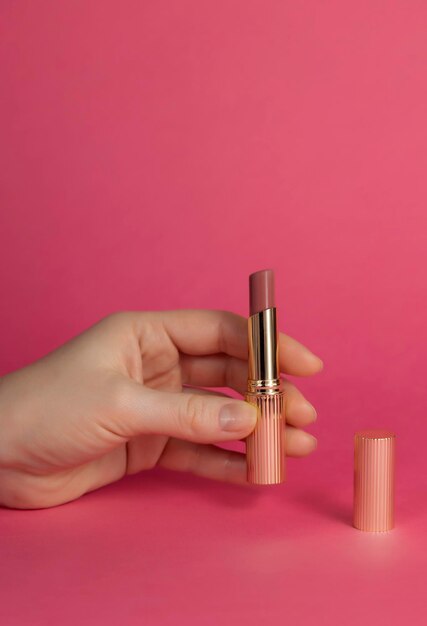 Open glossy tube of lipstick in female hand cosmetology concept