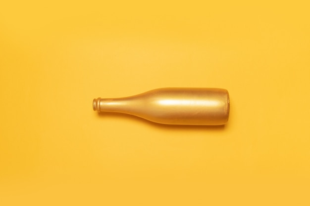 Open golden champagne bottle on yellow background