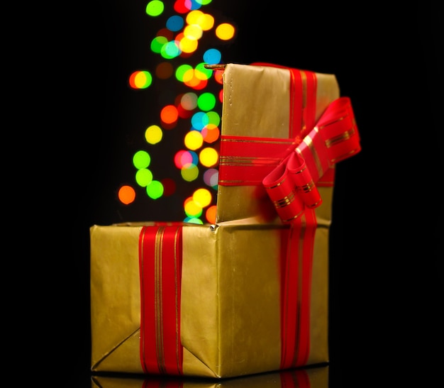 Open golden gift box with blurred lights on black