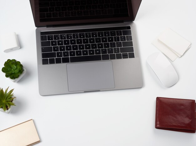 Open gray laptop stands on a white table, next to a wireless mouse, freelancer workplace, businessman, top view