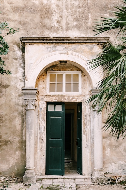 Open green doors with glass to the building with columns and an arch