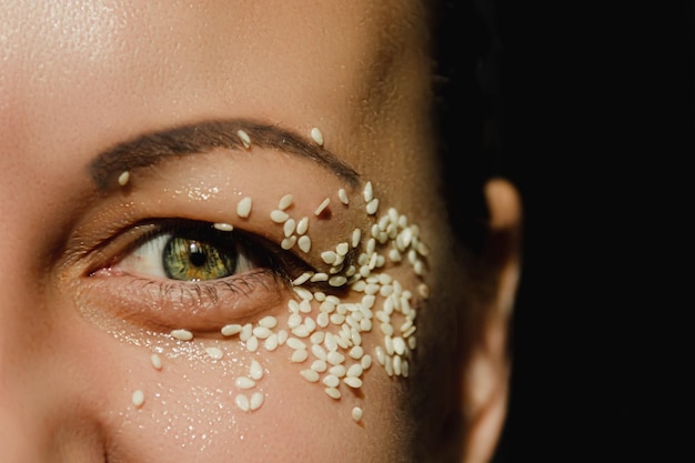 Open green eye of a woman with white sesame seeds on the eyelid around the eye Expressive look