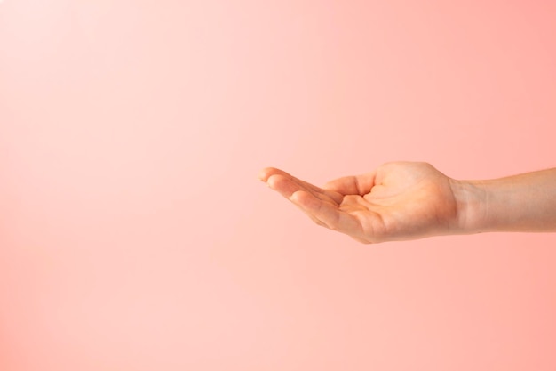 Photo open hand as if taking some object on pink background copy space