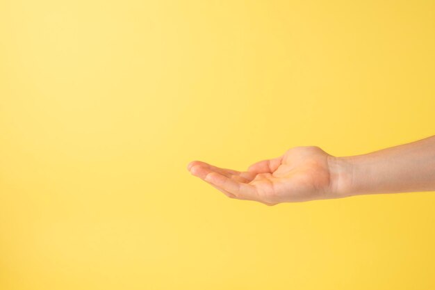 Photo open hand as if taking some object on yellow background copy space