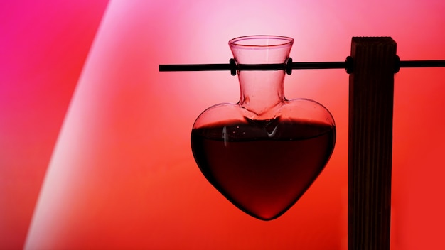 Open heart-shaped bottle of red love potion on a blurredred and pink background