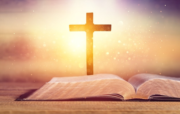 Open Holy bible book and cross on desk