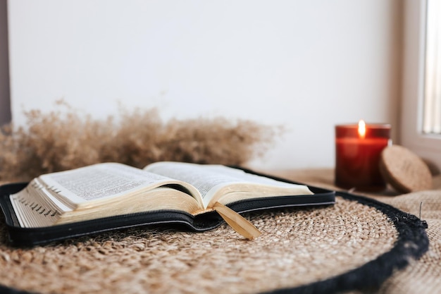 Open Holy Bible on a old wooden table and white wall background Religion concept Cozy warm photo