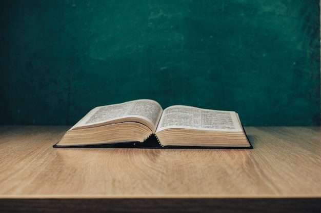 Open holy bible on a wooden table Beautiful green wall background