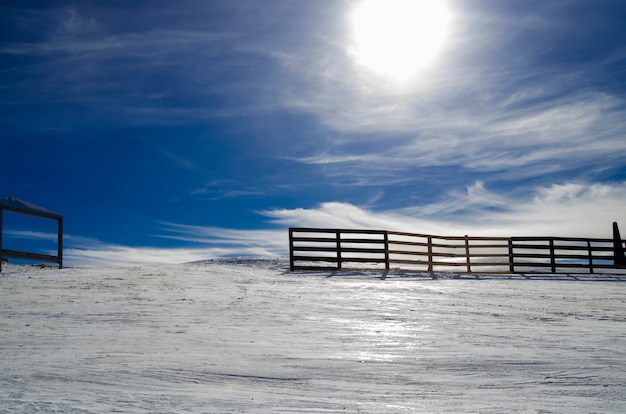 Open houten hek van boerderij op besneeuwde berg heuvel en prachtige winterlandschap