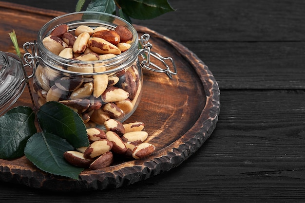 Open jar filled with Brazil nuts close up on a dark space