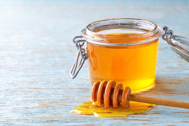 Open jar of   organic honey on a blue table, selective focus.