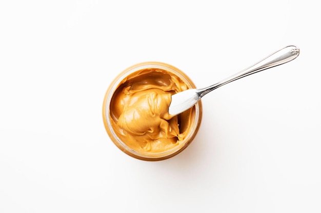 Open jar of peanut butter with spoon