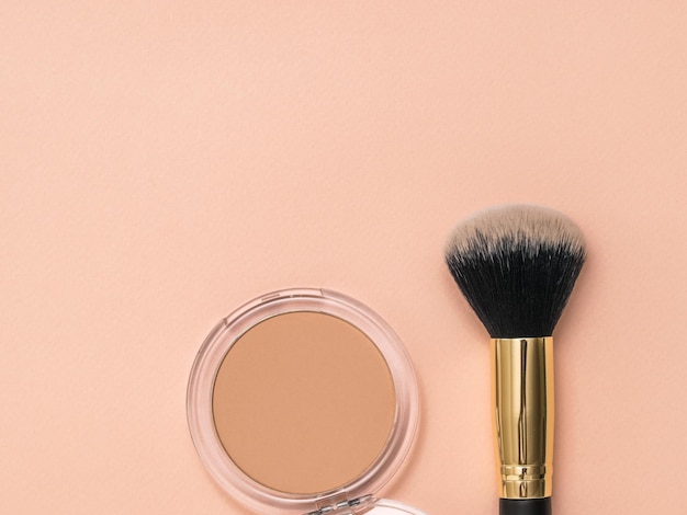 An open jar of powder and a makeup brush on a pastel background