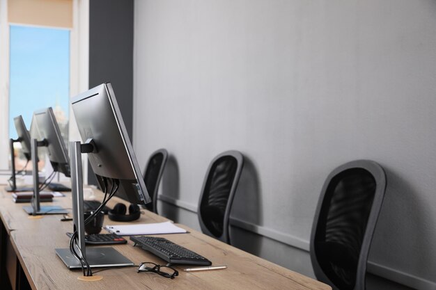 Open kantoorinterieur Moderne werkplekken met computers in de buurt van lichtgrijze muur