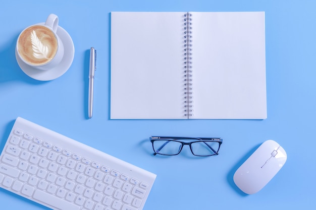 Open Kladblok met kantoorapparatuur en latte koffiekopje op Bureau.