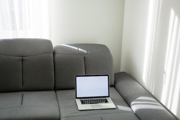 Photo open laptop on the couch. modern comfortable workplace, distance work. empty place for text, copy space.