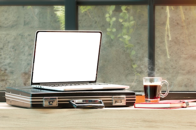 Open laptop, document bag, glasses at coffee shop.