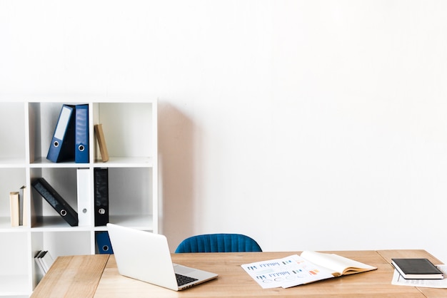 An open laptop and graph on wooden table in the office