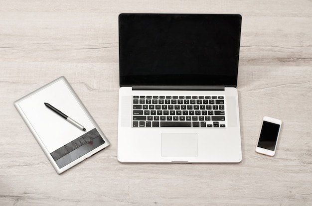 Open the laptop, graphics tablet and smart phone on a light table, top view