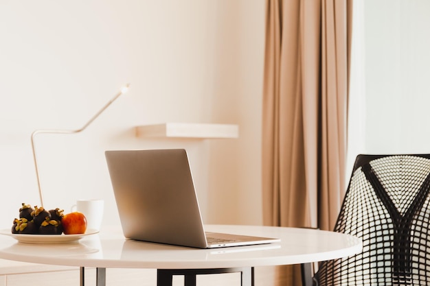 Open laptop op marmeren tafel in de woonkamer met vers fruit en koffiekopje