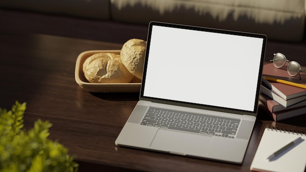 Open laptop screen mockup with book eyeglasses pen and decor on wood coffee table closeup