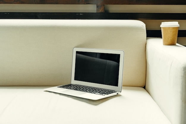 Open laptop on table near sofa home interior freelancer workplace concept