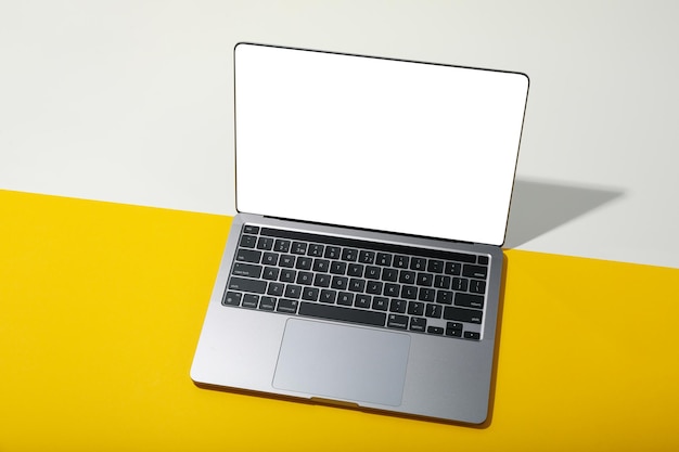 Open laptop with blank screen on yellow table