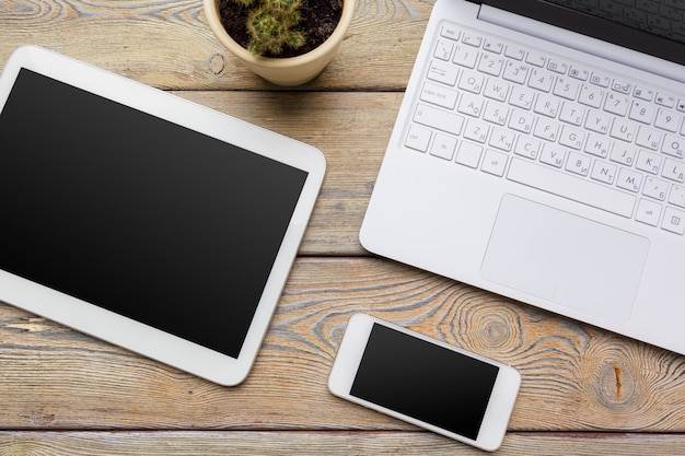 Открытый ноутбук с цифровой планшет и белый смартфон крупным планом вид сверху