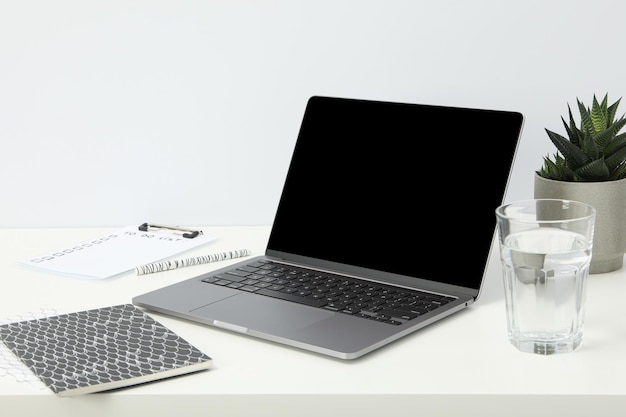 Photo an open laptop with a glass of water and a flower pot