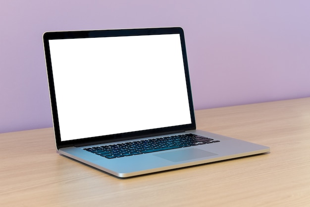 Open laptop on a wooden table on a lilac wall in office