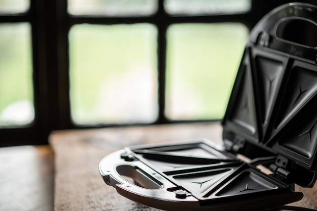 Open lege tosti-ijzer op de achtergrond van een ouderwets raam Koken toast Plaats voor tekst
