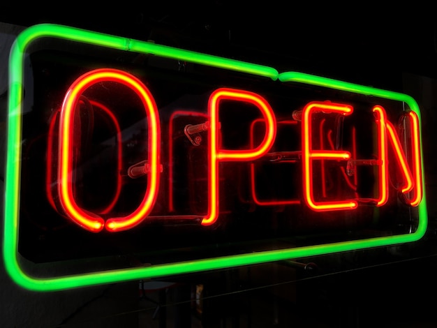 Photo open neon sign in shop or store window at night