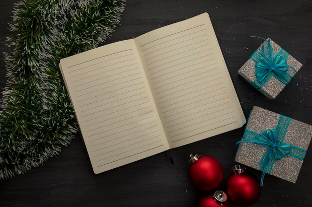 Open notebook on a black wooden background and christmas decoration