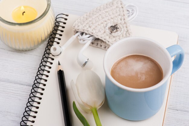 Open notebook, coffe, candle, earpods and tulip