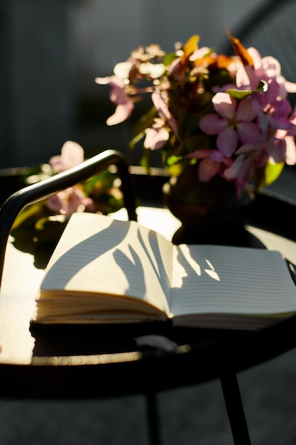 Open notebook and flowers and on the small black table on terrace